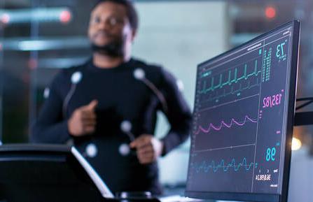 Male athlete runs on a treadmill with a close-up shot of EKG monitor.